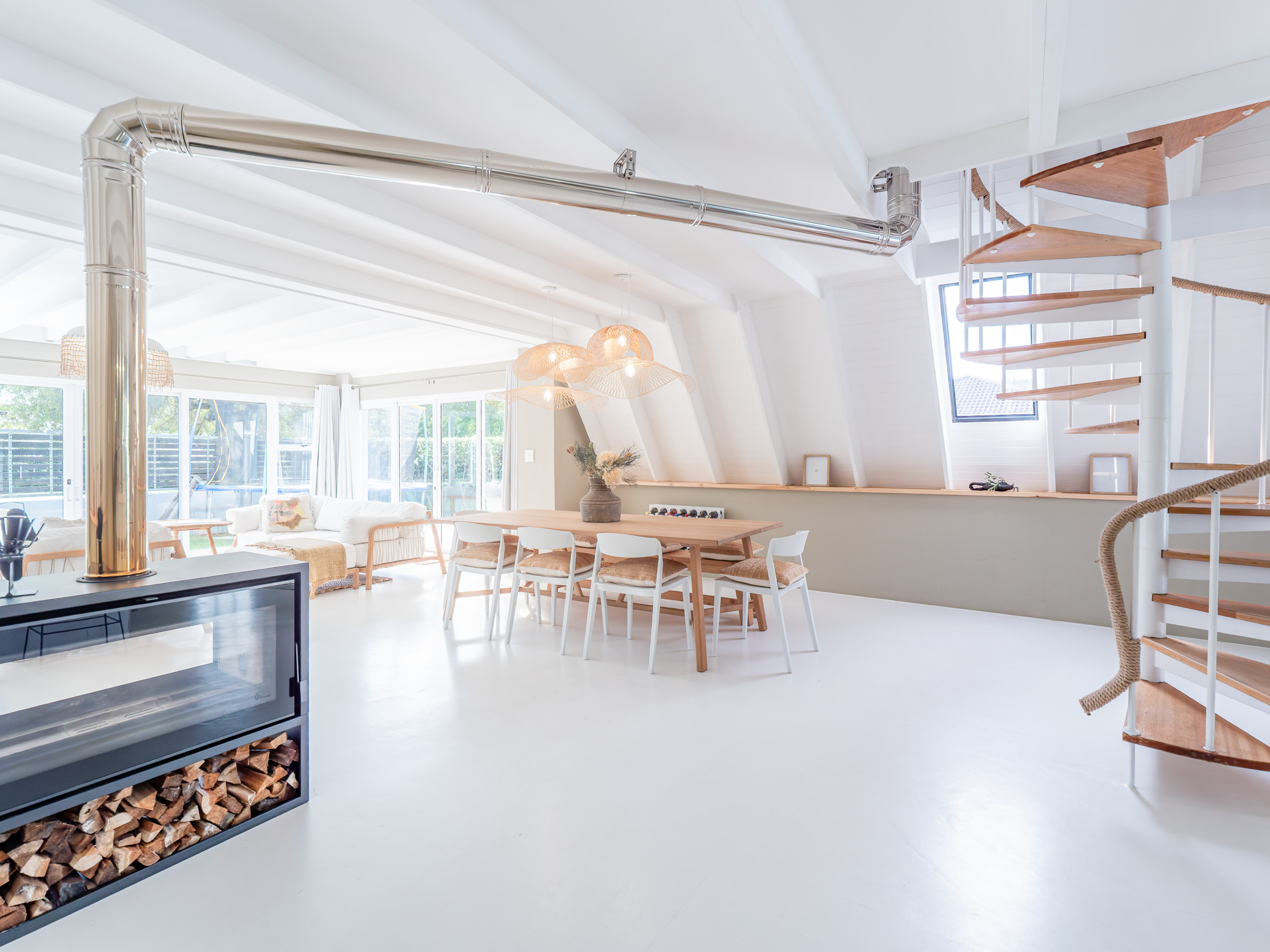 Bright open-plan living and dining space with a woodburner and spiral stair