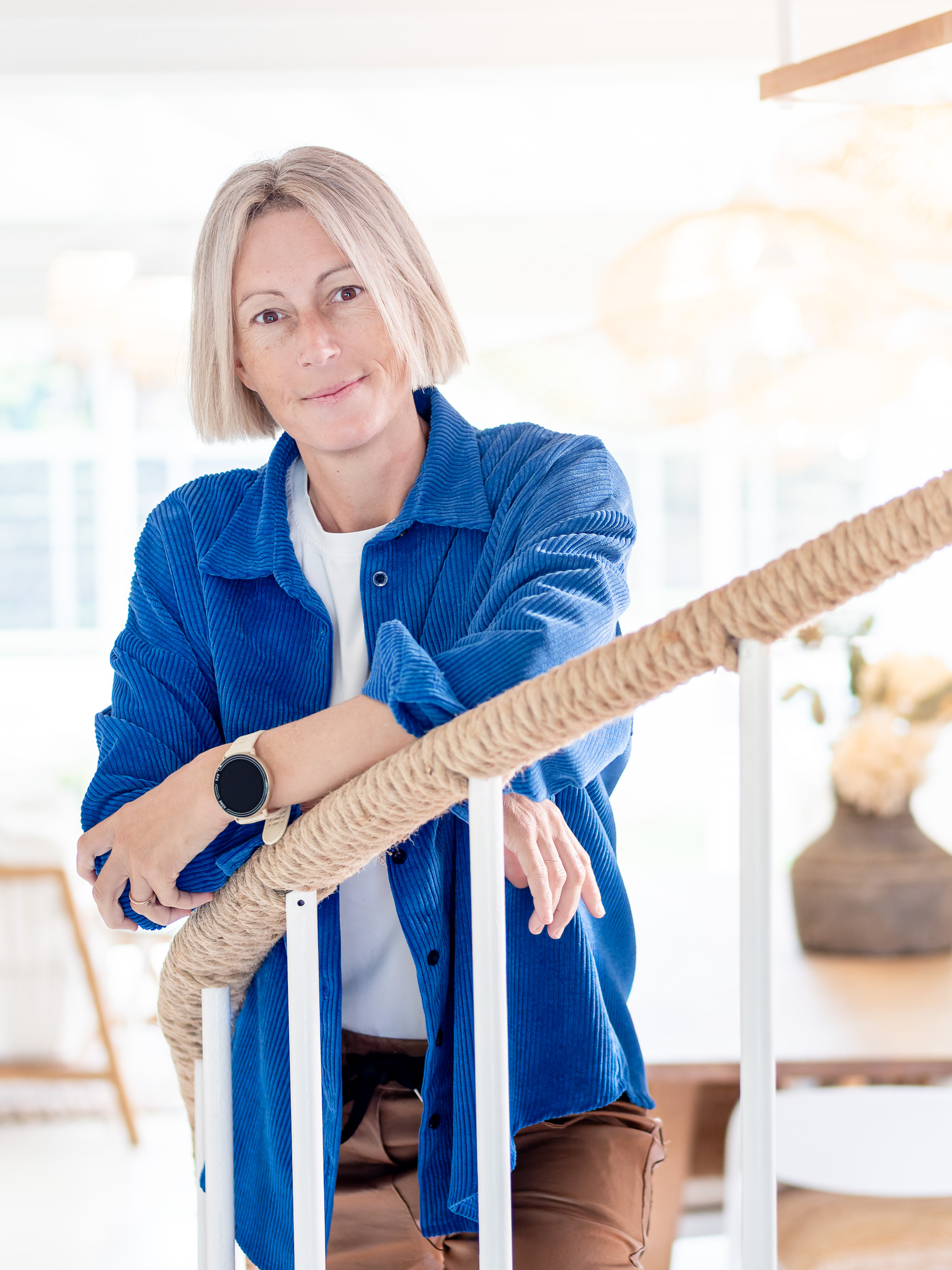 Yvonne, founder of Prakt., leaning on a staircase in a bright interior